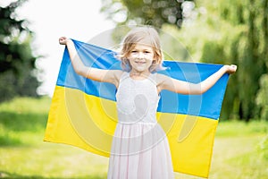 Child carries fluttering blue and yellow flag of Ukraine in wheat field. Ukraine& x27;s Independence Day. Flag Day