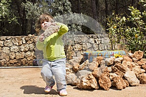 Child carying big rock in garden