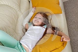 Child with a cast on a broken wrist or arm smiling and having fun on a couch. Positive attitude, recovery and kid