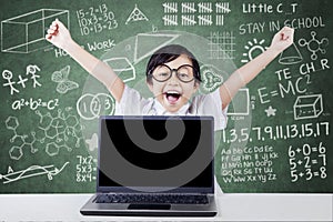 Child celebrate her success with laptop in class