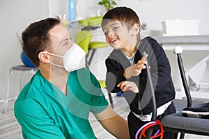 Child with cerebral palsy on physiotherapy in a children therapy center. Boy with disability doing exercises with