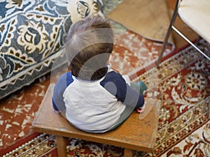 Child in a chair, rear view. Rear view of a little boy sitting on an old wooden chair, looking down