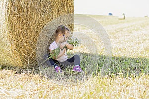 Child with chamomile near haystack