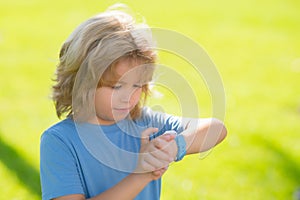 Child checking smart watch, looks on the time and hurrying. Portrait of kid checking time. Portrait of kid looks on