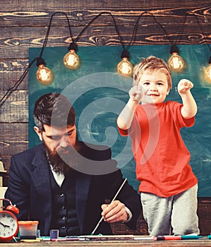 Child cheerful and teacher painting, drawing. Art lesson concept. Teacher with beard, father teaches little son to draw