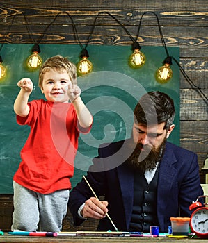 Child cheerful and teacher painting, drawing. Art lesson concept. Teacher with beard, father teaches little son to draw