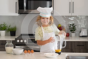 Child chef cook prepares food at kitchen. Kids cooking. Teen boy with apron and chef hat preparing a healthy meal.