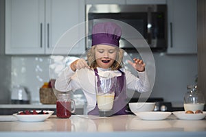 Child chef cooking meal. Chef child in apron and chef hat cooking at kitchen. Healthy food.