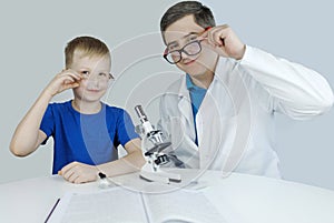 Child chemist. Teacher shows a visual experiment. A science mentor teaches an experimental approach. Microscope, petri dish,