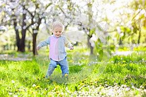 Child with cherry blossom flower. Easter egg hunt.