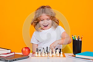 Child with chess on yellow isolated studio background. Kid playing chess. Clever child thinking about chess. Kids early