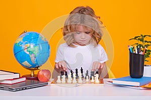 Child with chess on yellow isolated studio background. Little kid play chess. Thinking child. Chess game for kids