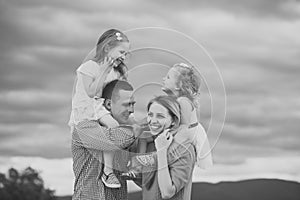 Child Childhood Children Happiness Concept. Girls sit on mother father shoulders on cloudy sky
