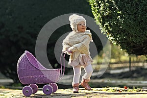 Child and childhood lifestyle. Girl walking with vintage doll stroller on sunny day