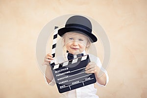Child with clapper board playing at home