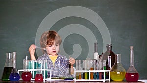 Child in the class room with blackboard on background. Chemistry lesson. Little kids scientist earning chemistry in