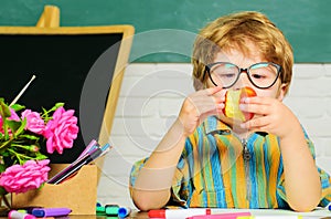 Child in classroom. School lunch. Cute kid eating apple. Boy from primary school at workplace.