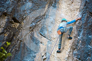 A child climber climbs on a rock photo