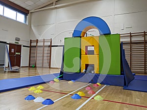 Child climbing into a base fort made of mats and pads