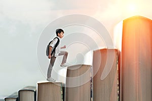 Child climbing stairs made of on sky background. Education or hard study concept. Soft focus