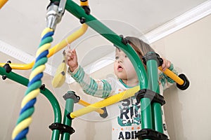 Child climbing to banana on gymnastic bar.Children workout. Child health care and physical training concept. Happy and healthy