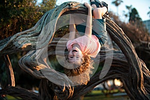 Child climbing tree. Smiling funny kid clim tree in the garden.