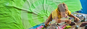 Child climbing on a wall in an outdoor climbing center BANNER, LONG FORMAT