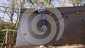 Child climbing on a wall in an outdoor climbing center. A boy in a rope Park.