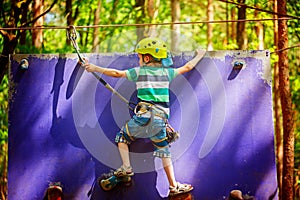 Child climbing on a wall in an outdoor climbing center in summer day