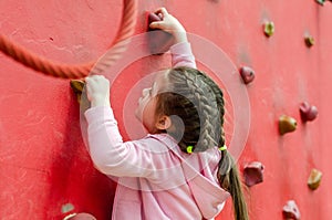 The child  climbs the climbing wall at the sports playground