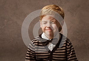 Child with closed eyes. Boy in brown retro bow tie