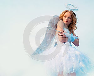 A child in the clothes of an angel on sky background - Valentine concept. Child with angelic character. Little angel