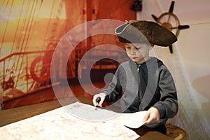 Child in cocked hat examines map