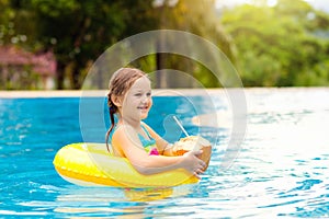 Child with coconut drink. Kids in swimming pool