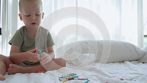 A child collects shapes from a constructor while sitting at home on a bed