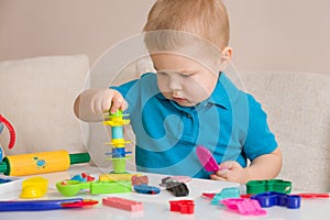 Child with colorful clay. Toddler playing and creating toys from play dough. Boy molding modeling clay