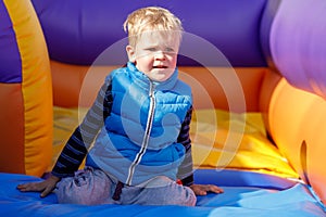 Child on colorful playground trampoline. Kid taking break in an inflatable bounce castle at a kindergarten birthday party.