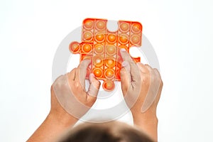 A child with a colorful pop it game. Anti-stress. A close-up shot of children& x27;s hands playing with the popular pop It