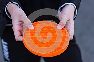 Child with colorful poppit game. Close up bunner shot of kid hands playing with colorful pop It fidget toy. Antistress toy