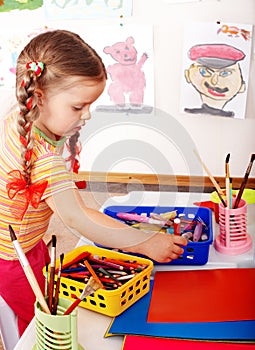 Child with colour pencil in play room.