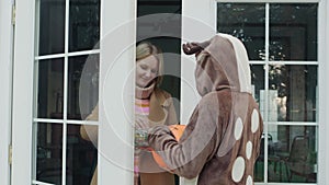 The child comes to get candy at the door of the house. Woman opens the door and gives a treat