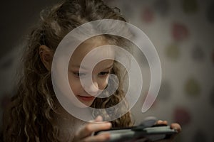 Child Concentration, Female Digital Native Looking Down Holding Technology. A concentrated female digital native looking down