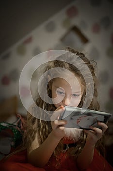 Child Concentration, Female Digital Native Looking Down Holding Technology. A concentrated female digital native looking down