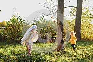 Child in a costume ghost in autumn park or forest. Halloween celebration holiday. yellow autumn, sunset