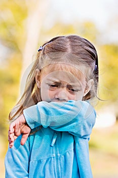 Child coughing or sneezing into arm