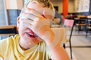 Child covering his surprise face with his hand while smiling