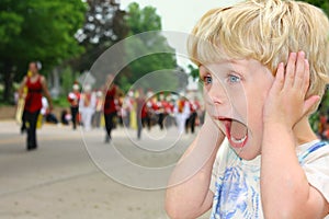 Child Covers Ears During Loud Parade photo