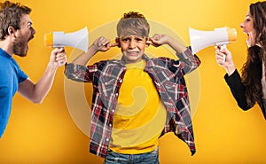 Child covers his ears because he does not want to hear the cries and reproaches of his parents. Yellow background