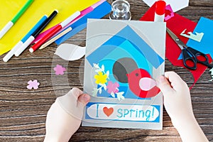 The child create a spring greeting card paper bird and birdhouse. Made by hand. Craft for kids.