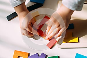 The child creates a figure from a colored puzzle on the table